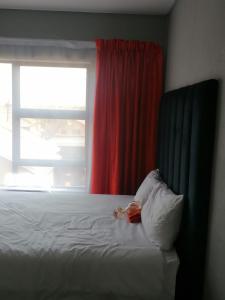 索韦托Serenity Guest House的一张带枕头的床和一个带红色窗帘的窗户