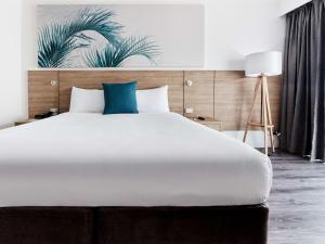 凯恩斯凯恩斯诺富特绿洲度假酒店的卧室配有一张白色大床和蓝色枕头