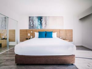 凯恩斯凯恩斯诺富特绿洲度假酒店的卧室配有带蓝色枕头的大型白色床