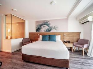 凯恩斯凯恩斯诺富特绿洲度假酒店的一间卧室配有一张大床和两把椅子