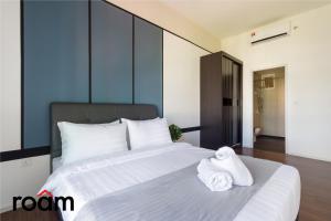 吉隆坡UNA Serviced Apartment Kuala Lumpur by Roam的卧室配有带毛巾的大型白色床