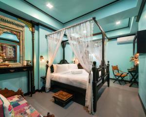 曼谷DE Phanakron Boutique Hotel的一间卧室配有一张天蓬床和一张桌子