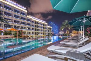 三亚三亚金都蔚景温德姆酒店（大东海）的夜间带椅子和遮阳伞的酒店游泳池