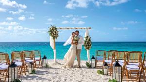 Shoal Bay VillageZemi Beach House, LXR Hotels & Resorts的一位新娘和新郎站在海滩上的一个婚礼拱下