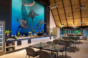 马累Dhawa Ihuru的一间餐厅设有桌椅和一面墙上的鱼