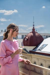 布拉格Almanac X Alcron Prague的站在一个装着葡萄酒杯的阳台上的女人
