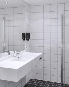 莫舍恩福如豪甘斯酒店的白色的浴室设有水槽和淋浴。