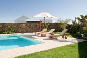 卡门港Beautiful Villa Ambar的一个带2把躺椅和遮阳伞的游泳池以及游泳池