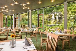 亚希莫夫阿斯托里亚酒店的餐厅设有桌椅,后方设有瀑布