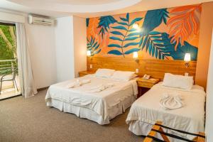 CapiatáLos Lagos Resort Hotel的墙上画画的房间里设有两张床