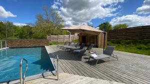 伊芙尔莱韦克Domaine de l'Epau Eco-Resort - Eco-Lodges的游泳池旁的甲板配有椅子和遮阳伞