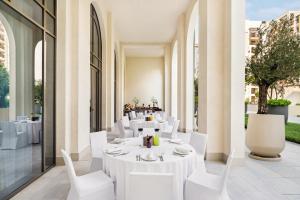 迪拜云溪港海滩葳达酒店的一间设有白色桌子和白色椅子的餐厅