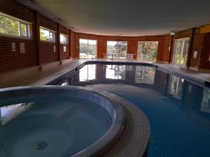 霍舍姆Roffey Park Institute的客房内设有一个大型游泳池及浴缸