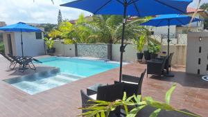 阿克拉KoKo Palm Inn的游泳池旁配有蓝色遮阳伞和椅子