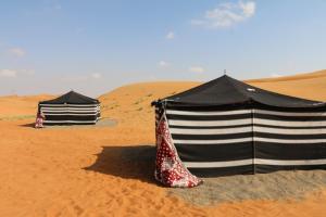 ShāhiqDesert Private Camps - Private Bedouin Tent的两个帐篷,位于沙漠的沙子中