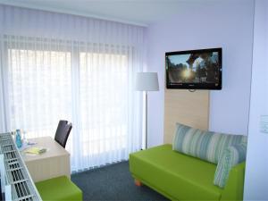 维尔茨堡布雷姆酒店的客厅设有绿色沙发和墙上的电视