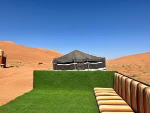 ShāhiqDesert Private Camps - Private Bedouin Tent的沙漠帐篷前的长凳