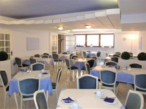 维尔茨堡布雷姆酒店的宴会厅配有桌椅和蓝色餐巾