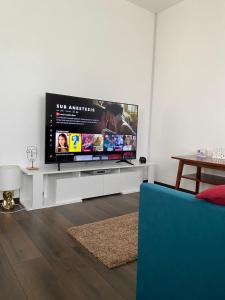 阿尔杰什河畔库尔泰亚Casa Eroilor的一间客厅,客厅内配有一台平面电视,位于白色娱乐中心