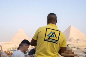 开罗大金字塔酒店 的穿着黄色衬衫的人看着金字塔