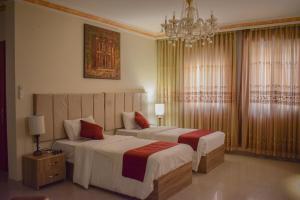 瓦迪穆萨Twilight Hotel Petra的酒店客房设有两张床和吊灯。