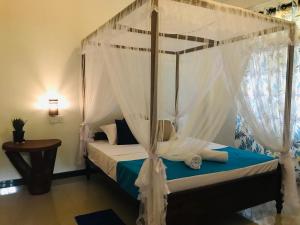 达瓦拉维Elephant Side Bungalow的卧室配有带白色窗帘的天蓬床