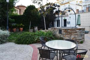 格拉纳达APARTAMENTOS CASERIA DE COMARES的庭院设有桌椅和石制壁炉。