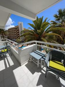 美洲海滩庞德罗莎公寓的阳台配有桌椅和棕榈树。