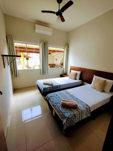 圣若昂-巴蒂斯塔-杜格罗里亚Pouso Oliveira Casa com ar condicionado的一间卧室配有两张床和吊扇