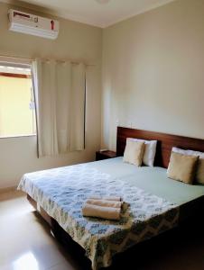 圣若昂-巴蒂斯塔-杜格罗里亚Pouso Oliveira Casa com ar condicionado的一间卧室配有一张大床和两条毛巾