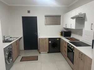 SandtonFun modern two bed apartment in fourways的白色的厨房配有洗衣机和烘干机