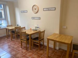 沃特福德Waterford Hostels Ltd的一间设有桌椅的用餐室和墙上的时钟