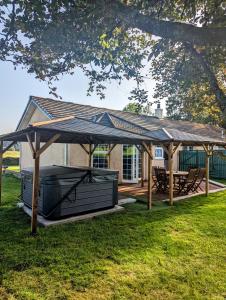 格拉斯哥FINN VILLAGE "Raspberry Cottage" Private Garden, 6-seater Hot Tub, Firepit & Pizza Stove的一个带野餐桌和长凳的大型木制凉亭