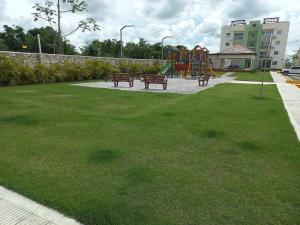 蓬塔卡纳Pool Breeze 202的草地上设有长椅和游乐场的公园