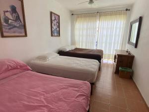 瓦兹特佩克Casa en Oaxtepec的一间卧室设有两张床、一张桌子和一个窗口