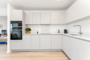伦敦Docklands Two Bed Apartment的白色的厨房配有白色橱柜和电器