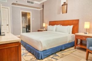巴拿马城Waymore Hotel Spa & Casino的卧室配有一张白色大床和一把椅子