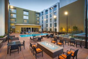 伯班克Hilton Garden Inn Burbank Downtown的一个带桌椅的户外庭院和一个游泳池