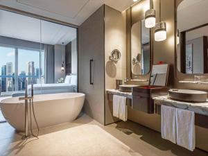 新加坡Swissotel The Stamford的带浴缸、两个盥洗盆和床的浴室