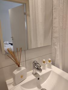 哥德堡Göteborgs Pärla的浴室水槽,上面有镜子和花瓶