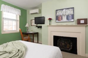 卡莱尔Carlisle House Bed and Breakfast的一间卧室设有壁炉、一张床和一台电视机。