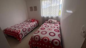 伊瓦格Hermoso Apartamento en exclusiva zona ibague Calambeo的红色和白色床罩的客房内的两张床