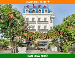 岘港Ngọc Bích Hotel Da Nang的一座白色的大建筑,上面有一堆鲜花