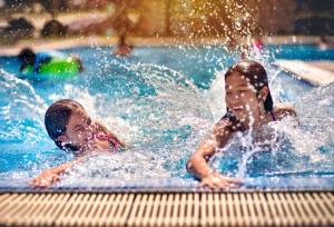 岘港Ngọc Bích Hotel Da Nang的两个小孩在游泳池玩耍