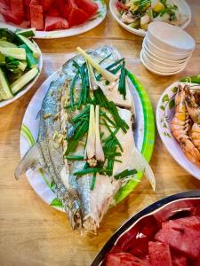 永熙THUẬN VƯƠNG Homestay的餐桌上放着鱼和西瓜等食物