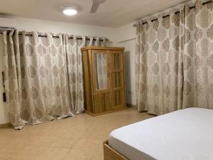 库马西Cozy One Bedroom Apartment near KNUST & CCC的一间卧室配有窗帘、一张床和橱柜