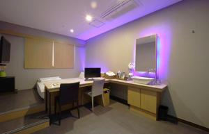 釜山Nampo Comma Hotel的客房设有一张桌子、一张床和镜子