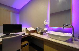 釜山Nampo Comma Hotel的一间带水槽的浴室和一张书桌上的电脑