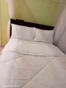 基苏木Wusiiza Homestay Kisumu的一张带白色床单和枕头的床