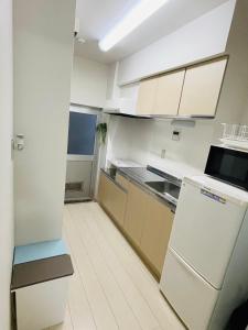 横须贺市STUDIO YONEGAHAMA l 米が浜通的厨房配有白色橱柜和冰箱。